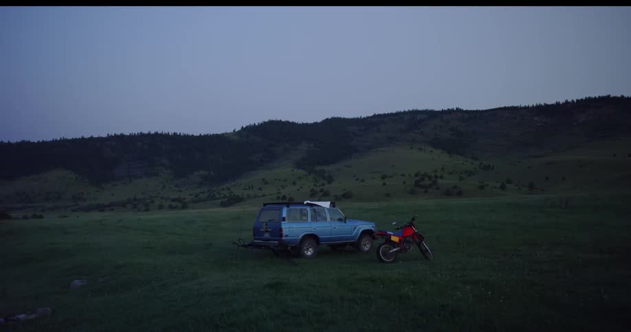 A dirt bike is parked near a vehicle on the field