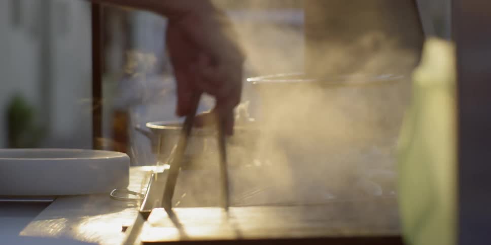 A man cooks some food next to a parked truck