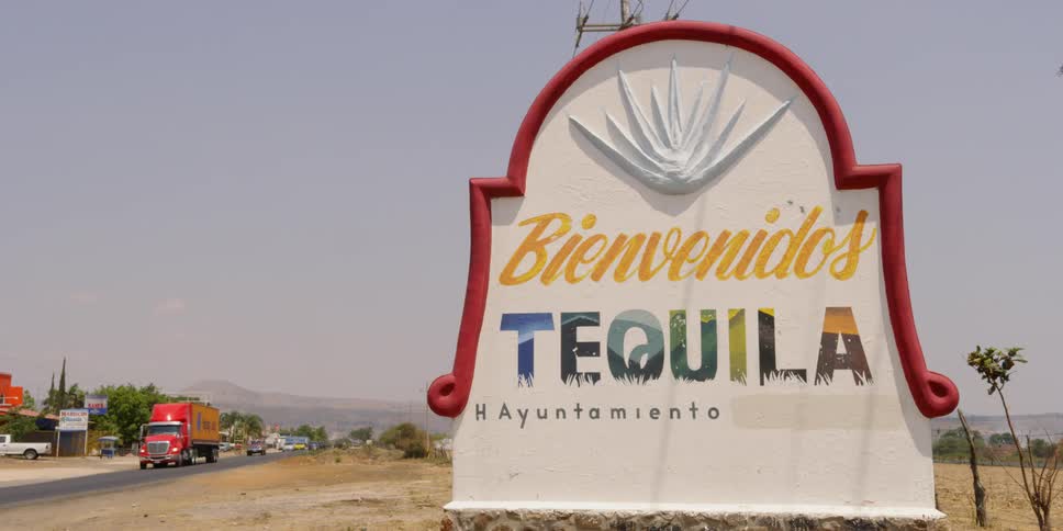 Cars drive by a sign in a town in mexico