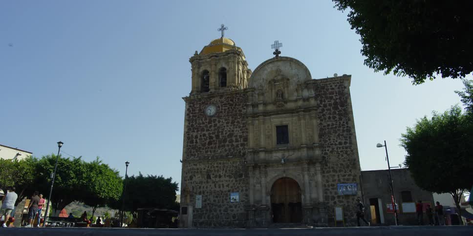People walk through a courtyard of a church (Parroquia Santiago Apostol)