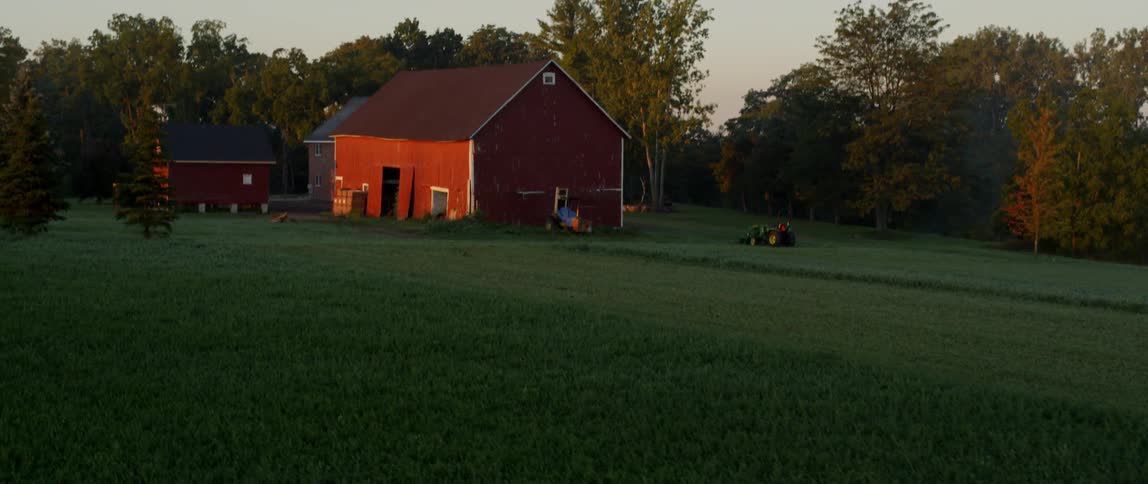 Two red barns sit near the trees