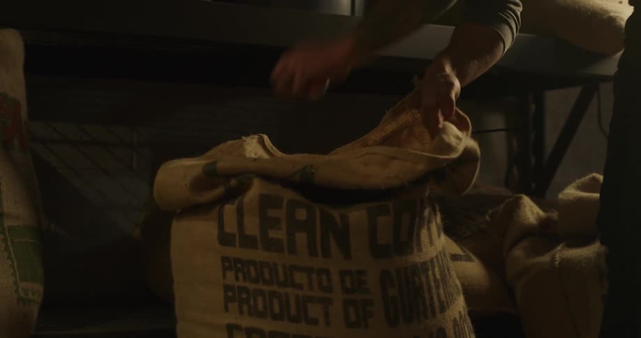 A person opens a sack of coffee beans
