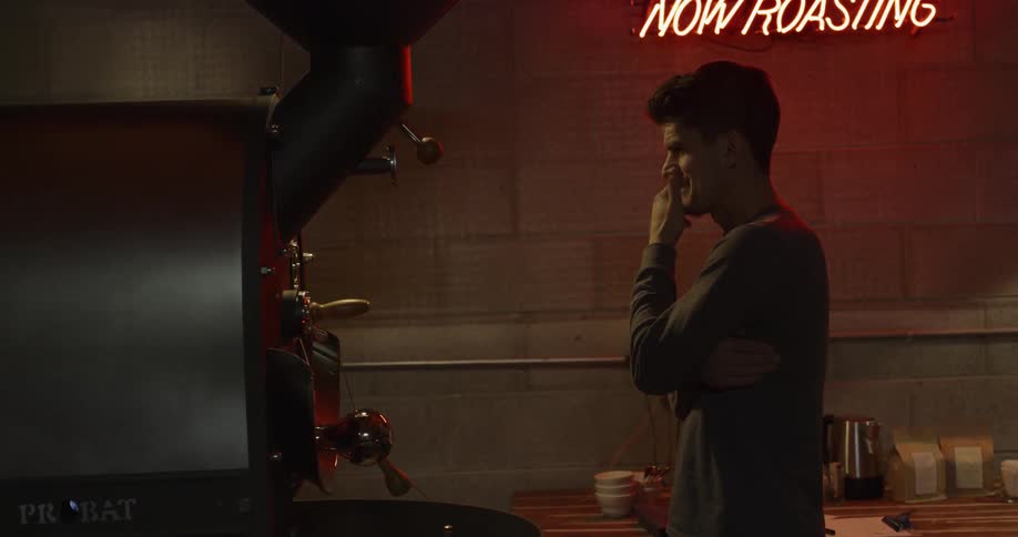 Man stands waiting near a machine in a room lit with neon sign
