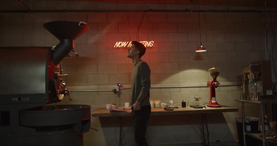Man stands near machine under now roasting sign