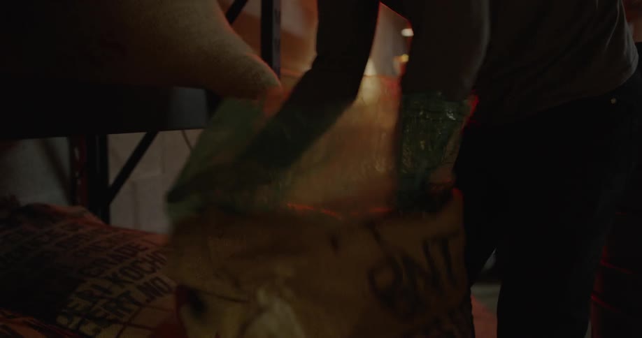 Long sleeved arms put their hands inside a plastic bag and open the plastic bag,it  is inside a drawstring bag of a light orange yellow color