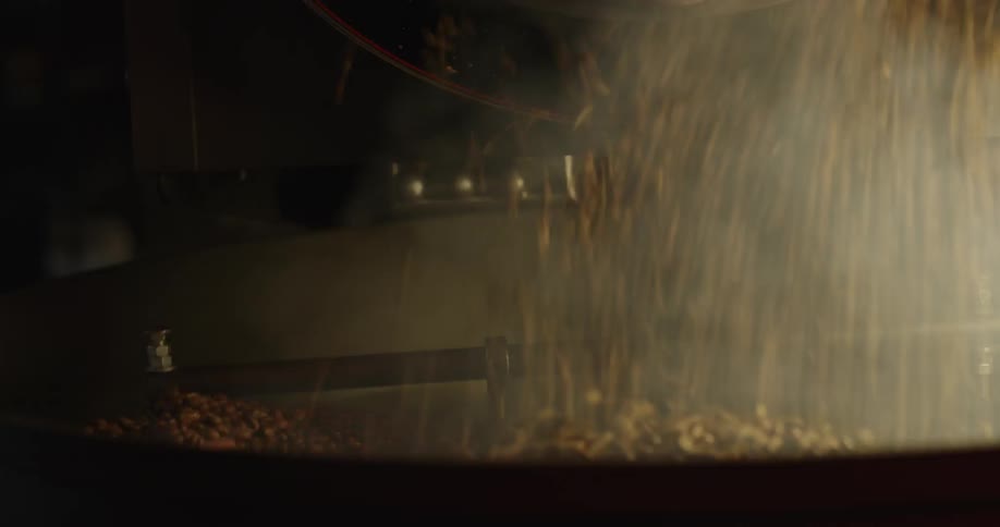 Coffee beans are pouring into the large roaster