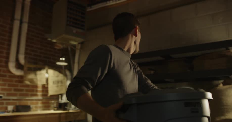 Man puts a lid on a garbage pail and puts the pail on a shelf