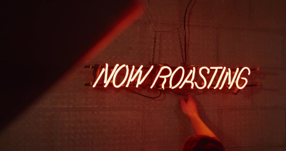 A man turns a sign on reading "now roasting"