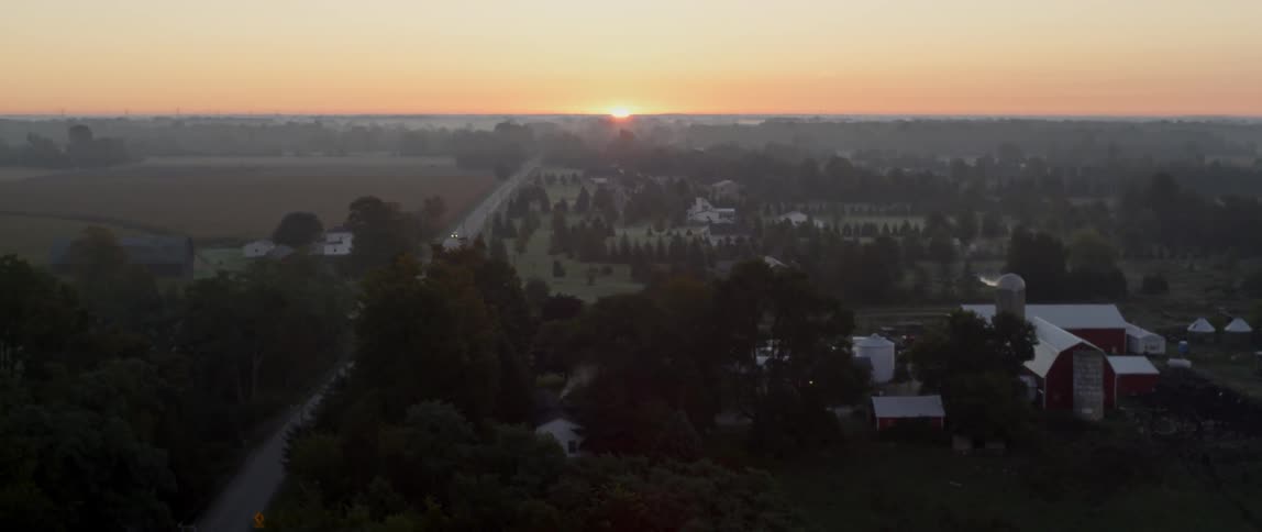 The sun sets over a rural farm