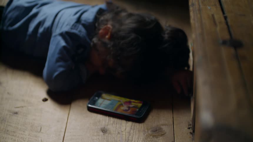 A person laying on the floor watching a smartphone