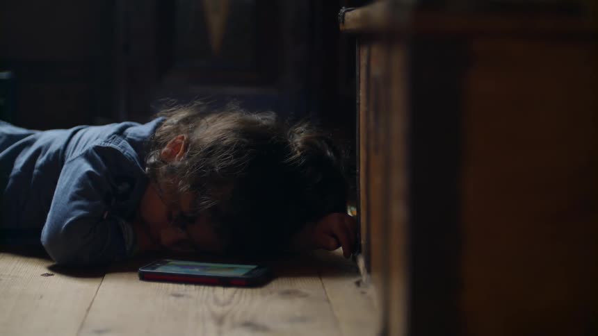A child is laying down sleeping near a cell phone