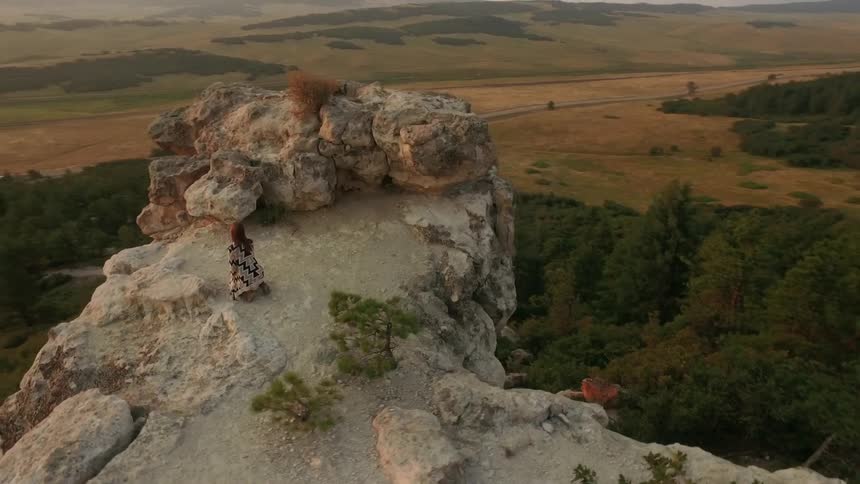 A woman standing on top of a big rock cliff at desert