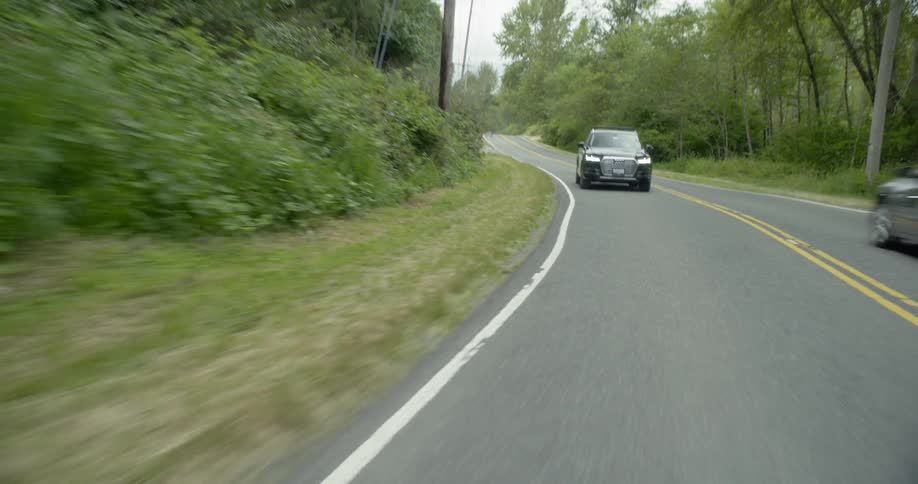 Cars travel on a rural tree lined road