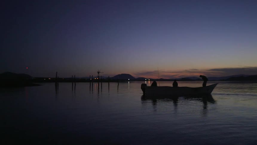 Three people ride in a canoe at sunset