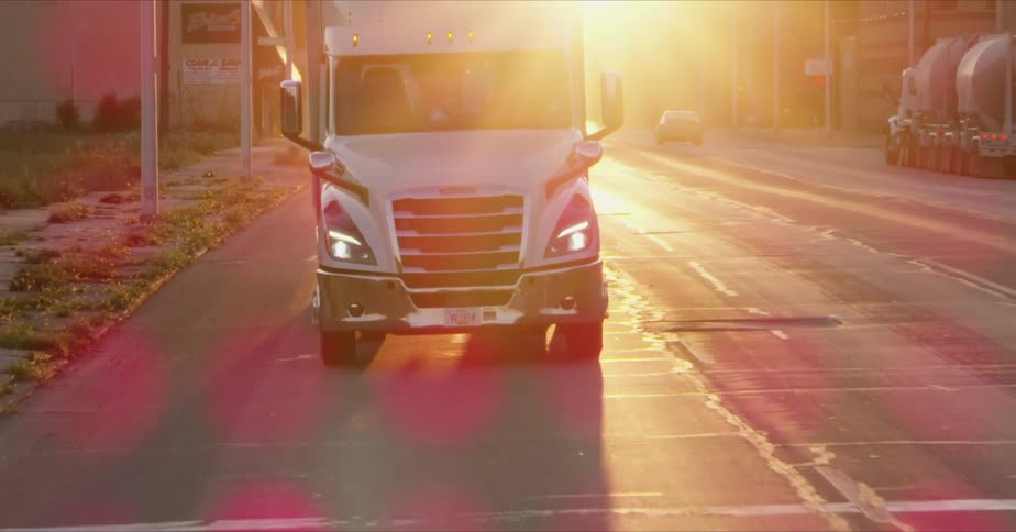 Silver truck going down the street at sunset