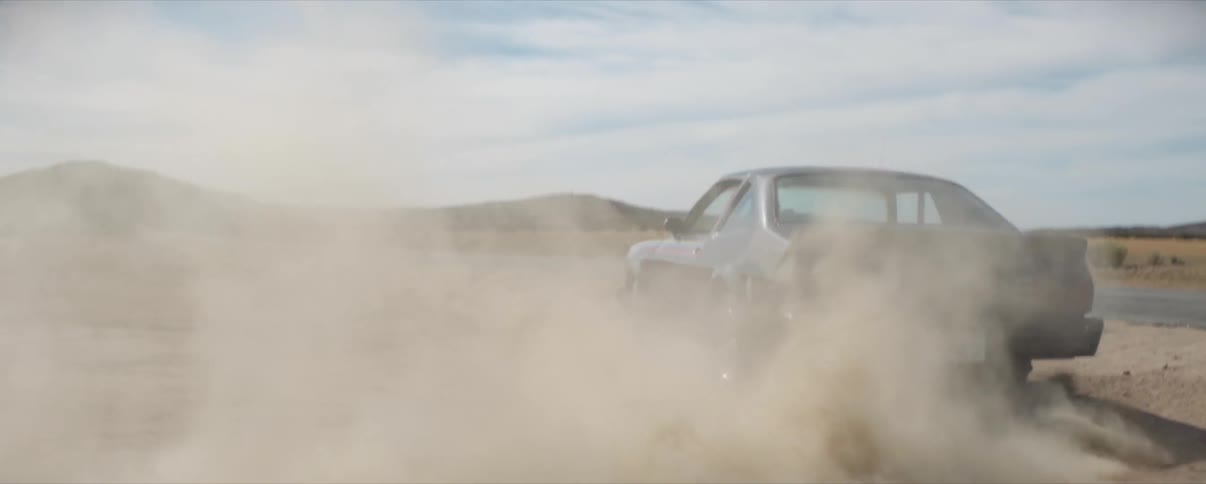 Classic Muscle Car doing donuts burnout In dirt