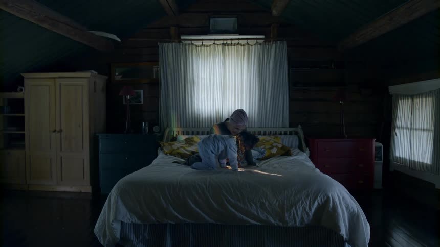 Woman and child are sitting on a bed indoors