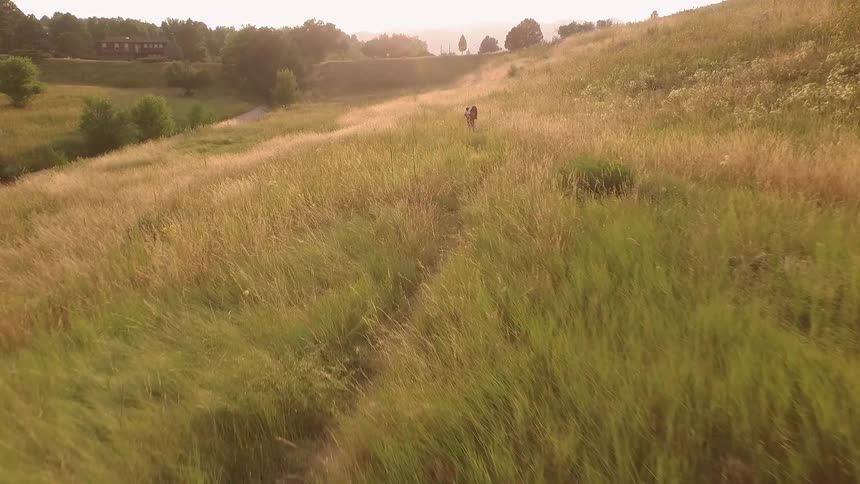 A woman and baby walking in a grassy field
