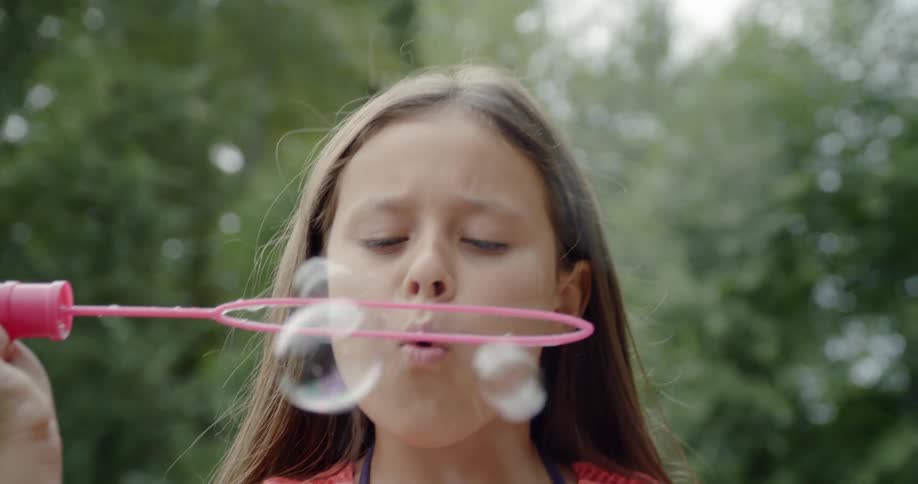 Girl plays with bubble maker outdoors