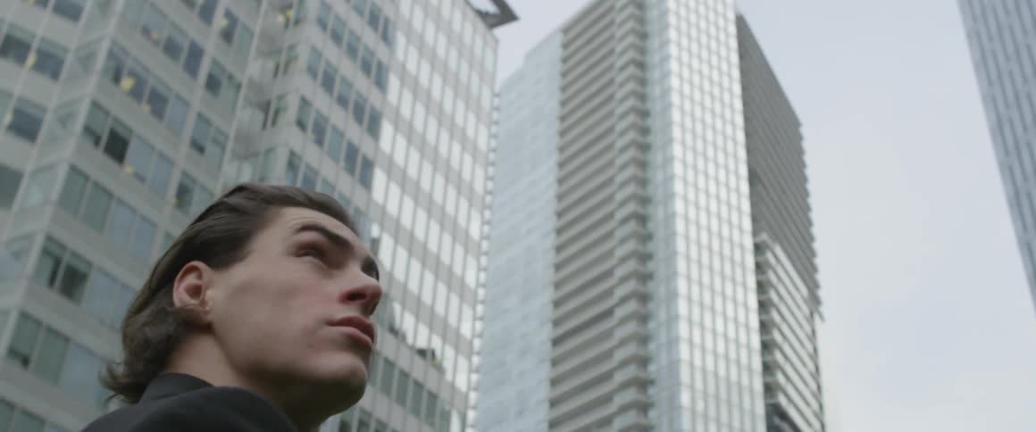 The man walks in the city looking up at the buildings