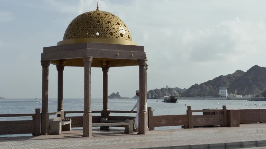 A man passes by an arabesque gazebo at the shore