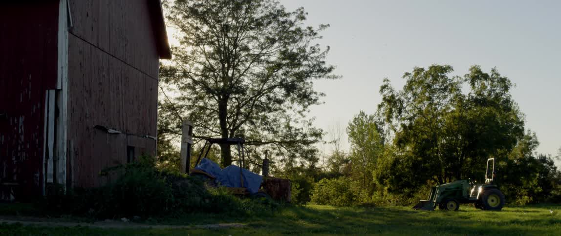 The sun is setting behind the large barn