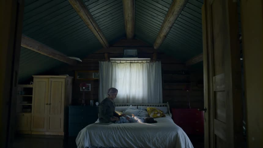 An old woman tickles a baby on a bed