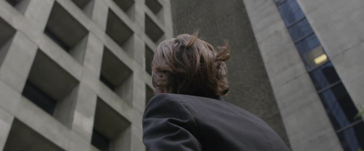 Man looks up at the buildings as he stands in the city