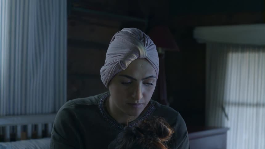 A mother and daughter read a book in bed