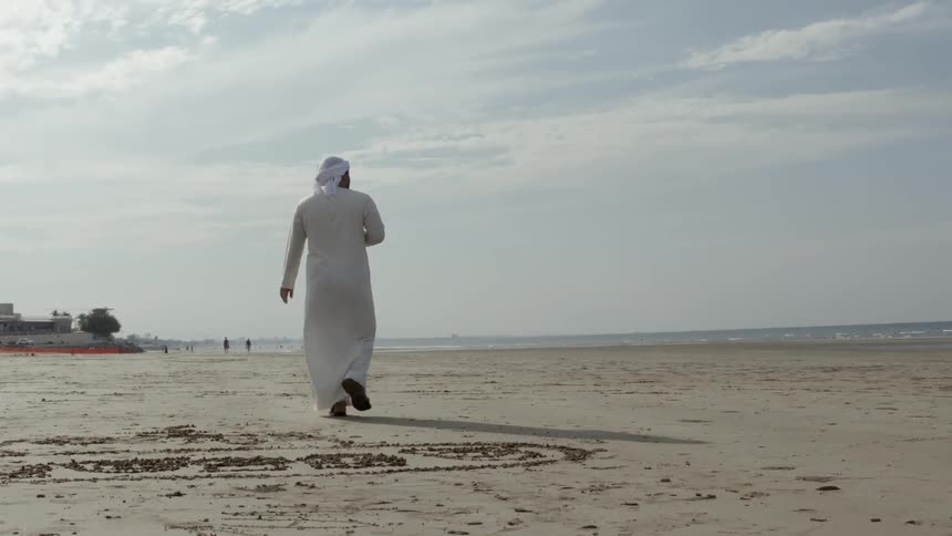 A man is walking on a beach outside