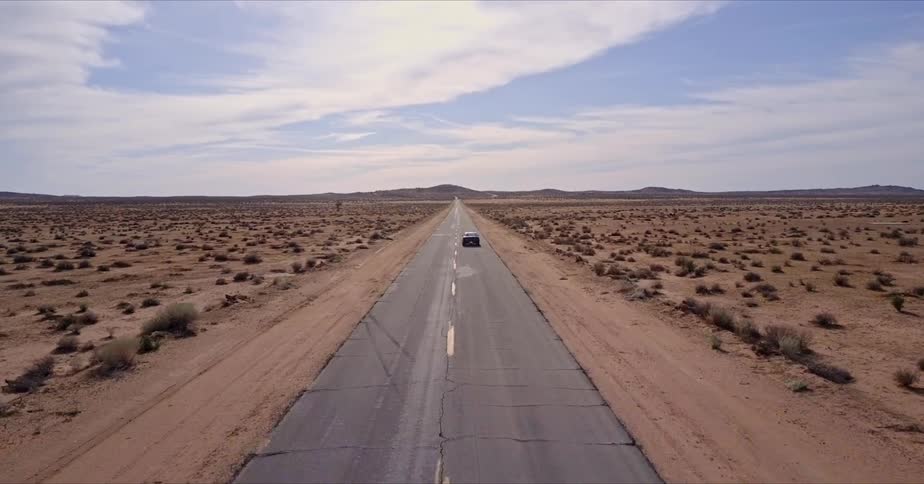 A car zooms along a street in a sunny desert