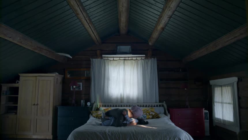 A parent and child play in bed together