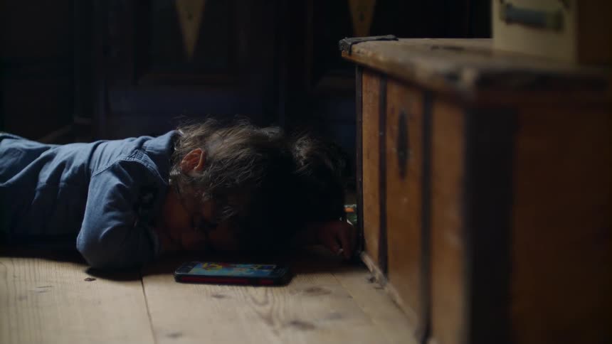 Person lays on a wooden floor with a phone next to them