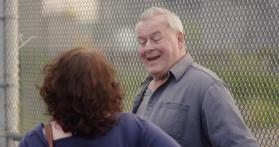 A man talks with a woman near a fence