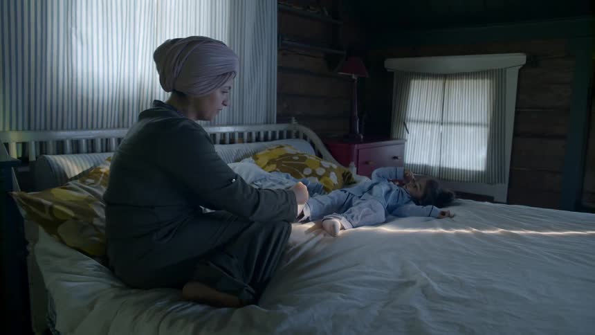 A mother rubs her daughter's legs in bed