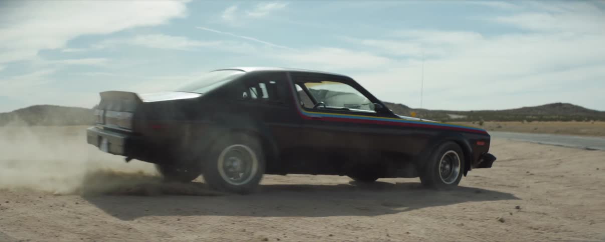 A man drives donuts in a classic car in a desert