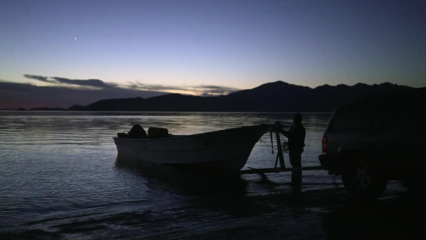The person is pulling rope from a boat on the shore line