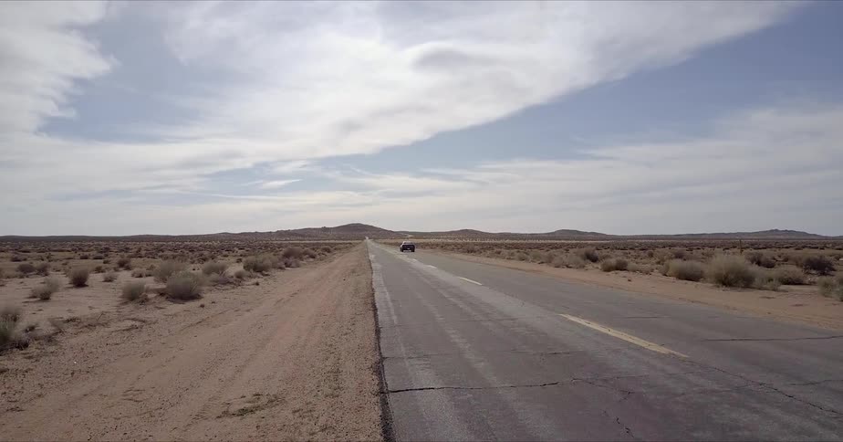 Car pulling onto the side of the road in a desolate desert while being passed by another vehicle