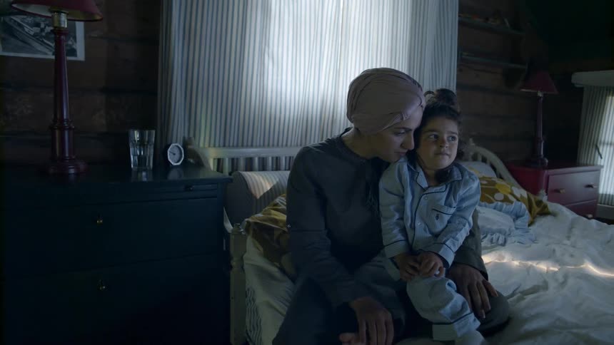 Woman and young child rock as they sit on the bed