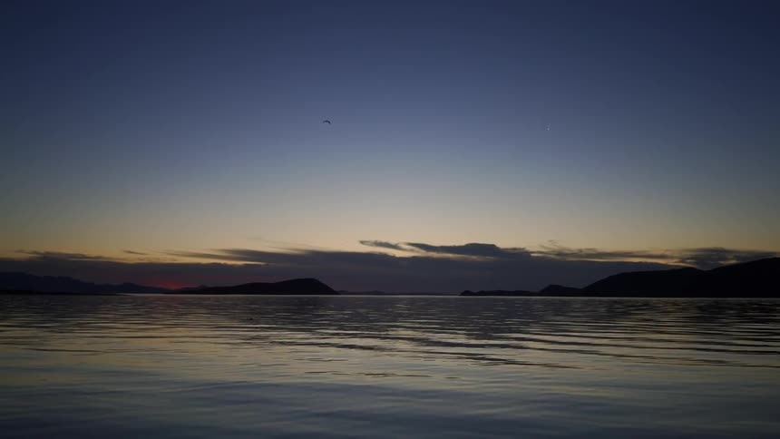 The sun is setting in the horizon above the ocean