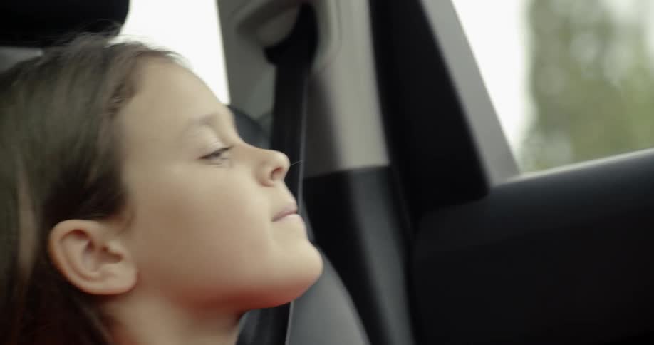 A child stretches to see out the window of the car