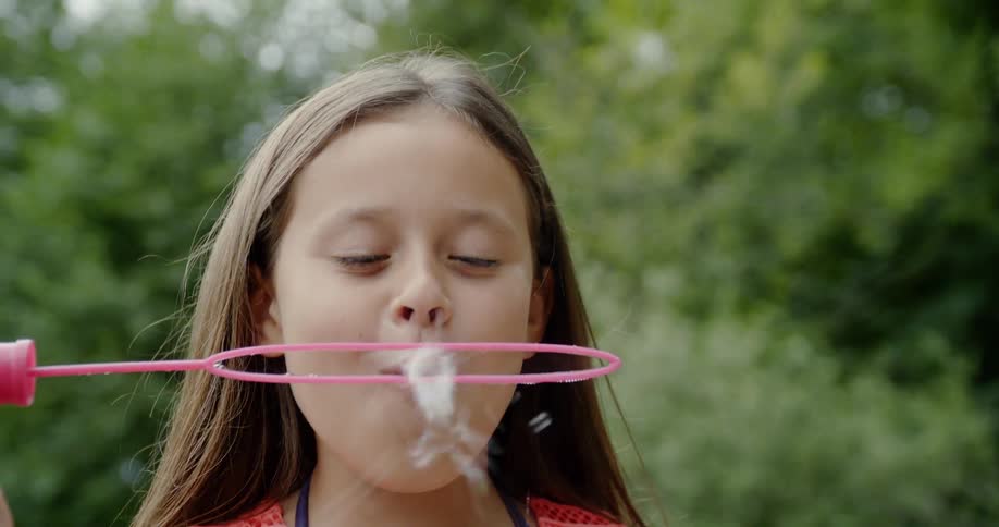 Girl having fun and playing with a soap bubble toy