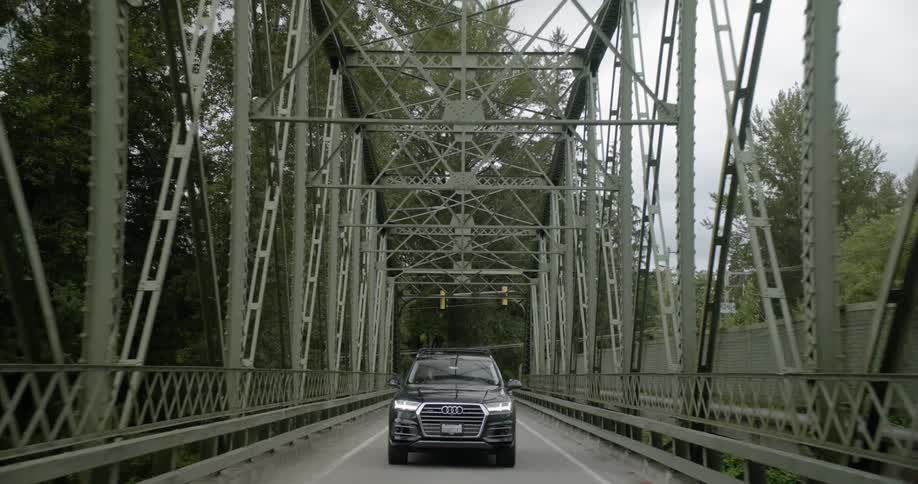 A vehicle travels over a narrow bridge