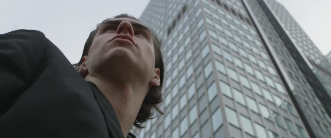 Man looks around in city among tall buildings