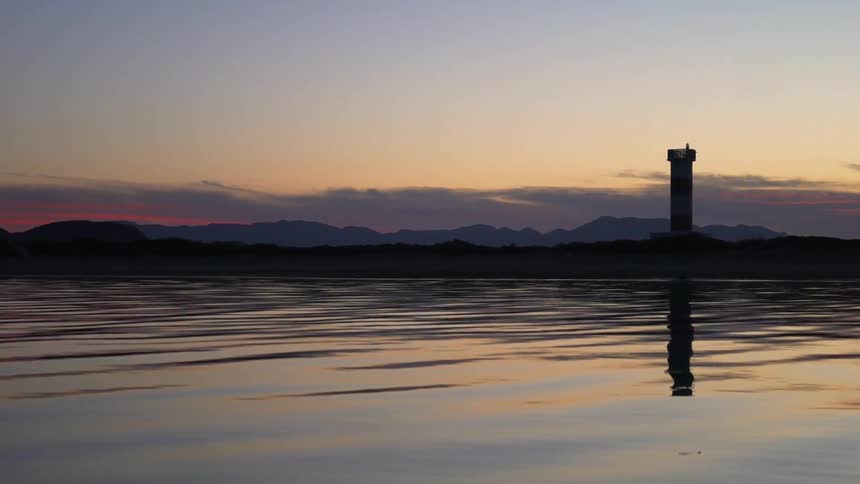 A tower sits at the end of the lake at sunset