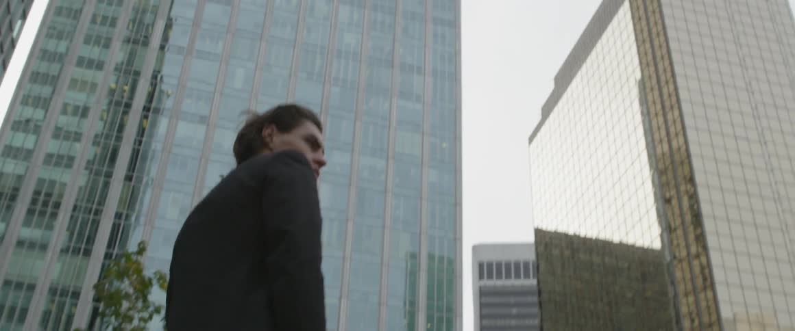 A man in a suit walks near tall skyscrapers