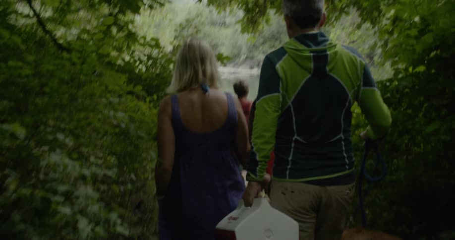 A family walks with their dog towards the lake