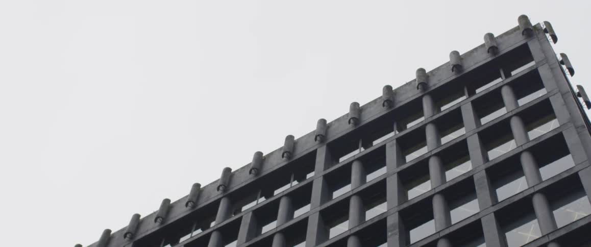 The building has many windows with a railing on the roof