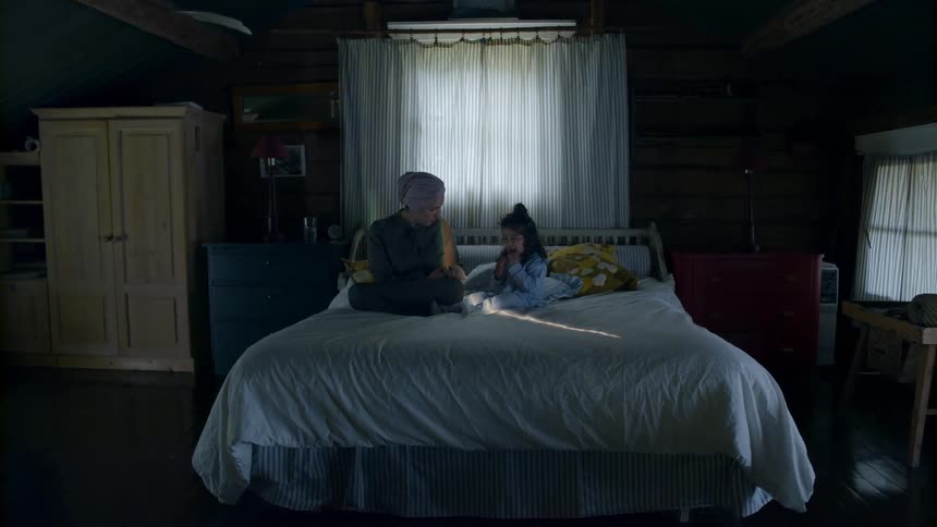 A woman and a girl sit on a bed and talk