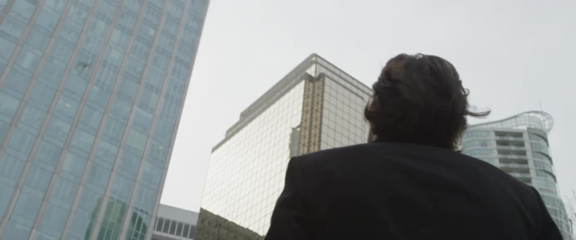 Man staring up at a tall high rise building
